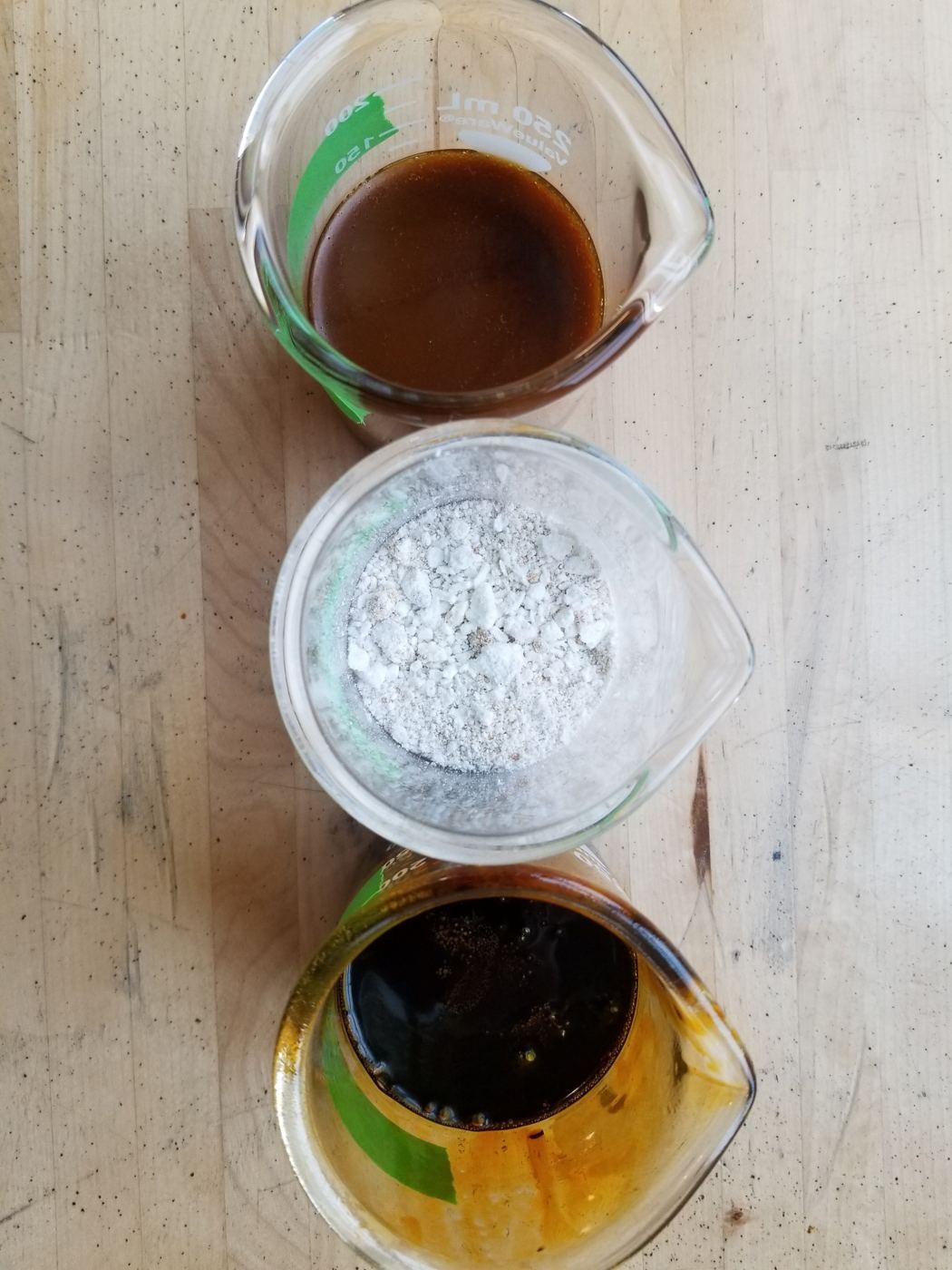 Three beakers holding crude extract, recovered wax, and dewaxed oil